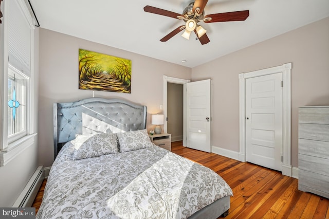 bedroom with hardwood / wood-style floors, a baseboard radiator, and ceiling fan