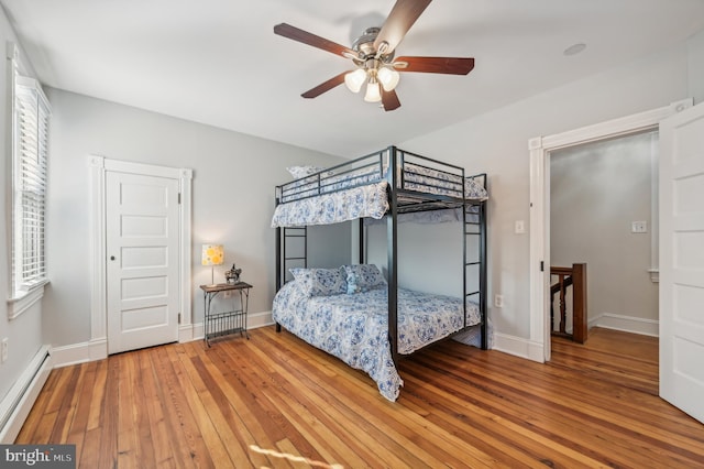 bedroom featuring hardwood / wood-style flooring, a baseboard radiator, and ceiling fan