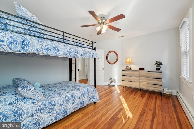 bedroom with hardwood / wood-style floors, ceiling fan, and baseboard heating