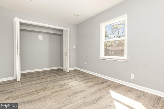 unfurnished bedroom with light wood-type flooring and a closet