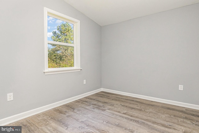 unfurnished room featuring hardwood / wood-style flooring and lofted ceiling