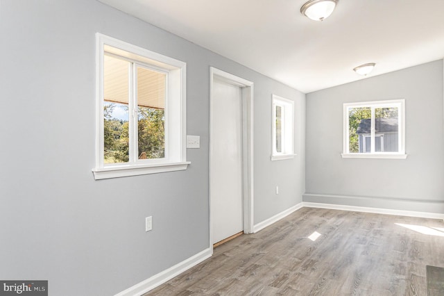 empty room with lofted ceiling, light hardwood / wood-style floors, and a healthy amount of sunlight