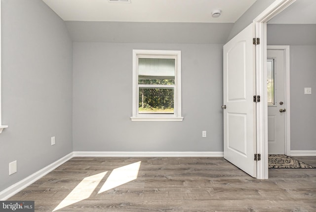 empty room featuring vaulted ceiling and light hardwood / wood-style flooring