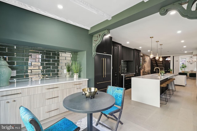 kitchen with tasteful backsplash, a breakfast bar, a kitchen island with sink, stainless steel range, and built in refrigerator