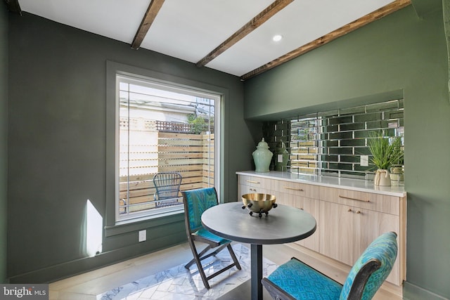 dining area with light hardwood / wood-style floors and beamed ceiling