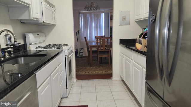 kitchen with light tile patterned floors, white cabinetry, a chandelier, sink, and white appliances