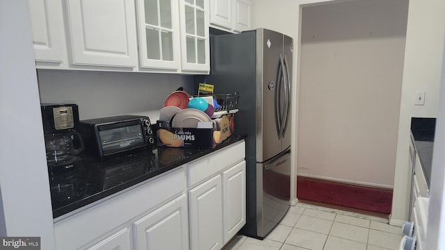 kitchen featuring stainless steel fridge, white cabinets, and light tile patterned floors