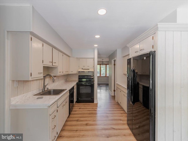 kitchen featuring decorative backsplash, light hardwood / wood-style flooring, sink, black appliances, and a baseboard radiator