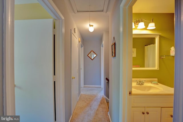 hallway featuring sink and light colored carpet