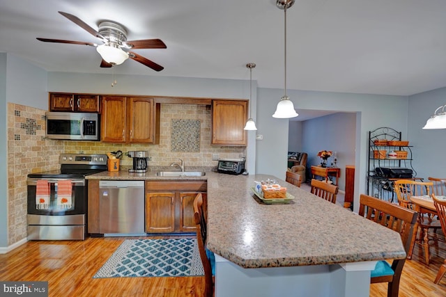 kitchen featuring pendant lighting, light hardwood / wood-style floors, sink, and stainless steel appliances