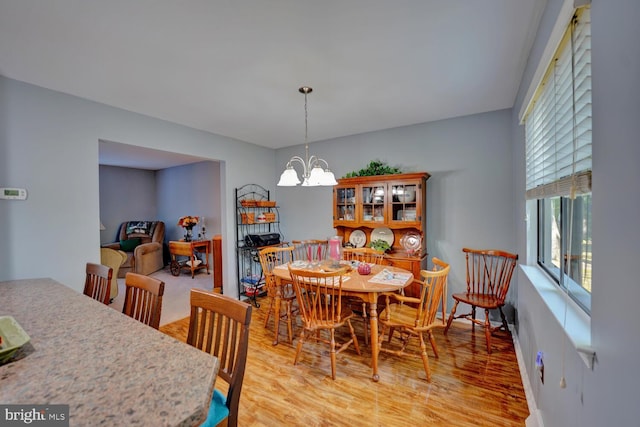 dining area with light hardwood / wood-style floors and a chandelier