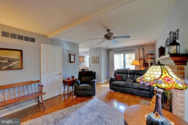 living room featuring wood-type flooring, a fireplace, and ceiling fan