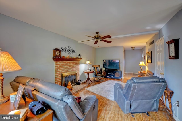 living room with a fireplace, ceiling fan, and light hardwood / wood-style flooring