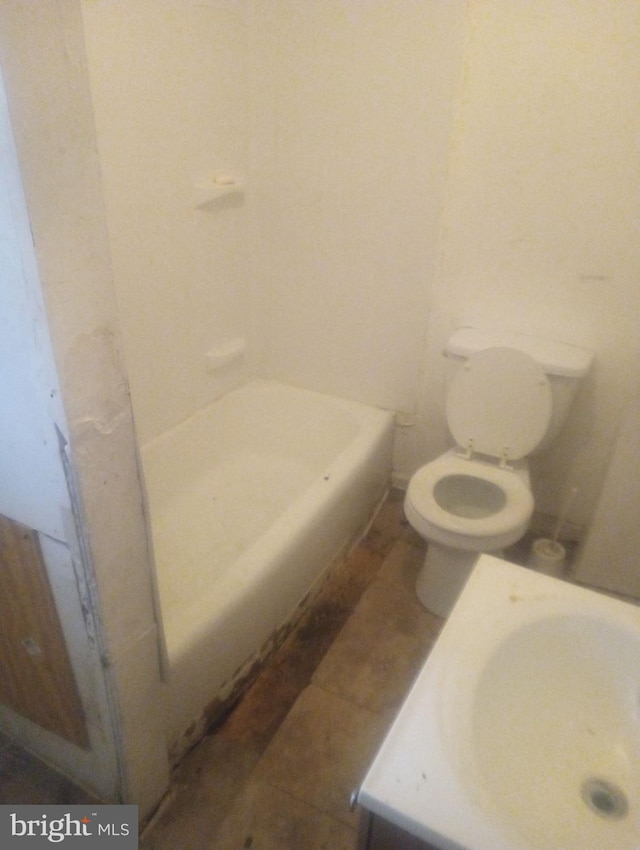 bathroom with a washtub, vanity, and toilet