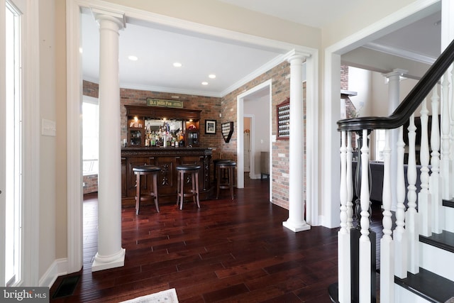 bar with dark hardwood / wood-style floors, crown molding, and brick wall