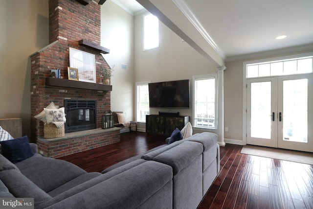 living room featuring ornate columns, french doors, a brick fireplace, dark hardwood / wood-style floors, and ornamental molding