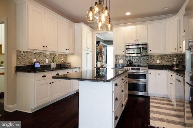 kitchen featuring appliances with stainless steel finishes, dark hardwood / wood-style flooring, a kitchen island, decorative light fixtures, and white cabinetry