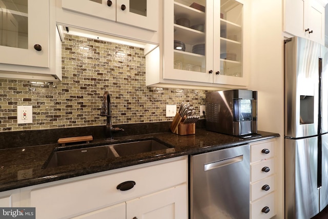 kitchen featuring sink, dark stone countertops, tasteful backsplash, white cabinetry, and stainless steel appliances