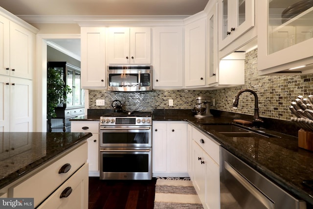 kitchen featuring decorative backsplash, dark stone counters, stainless steel appliances, sink, and white cabinets