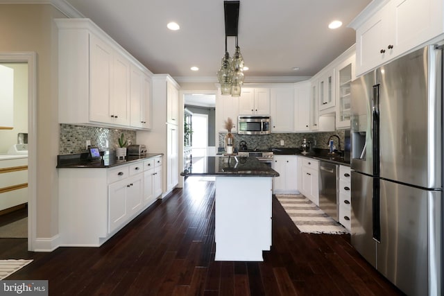 kitchen featuring white cabinets, appliances with stainless steel finishes, decorative light fixtures, and a kitchen island