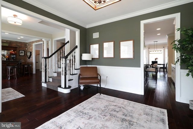 entrance foyer featuring ornamental molding, decorative columns, dark wood-type flooring, and brick wall