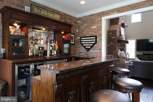 bar with dark brown cabinetry, wine cooler, and brick wall