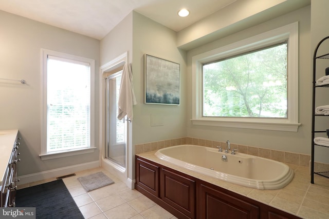 bathroom featuring independent shower and bath, tile patterned flooring, vanity, and a healthy amount of sunlight