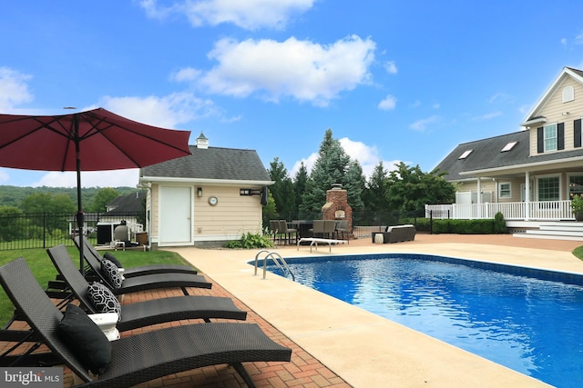 view of swimming pool with a fireplace, a patio, and an outdoor structure