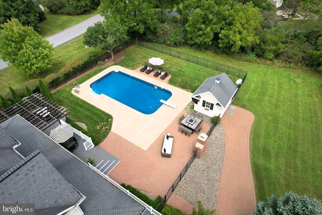 view of pool featuring a patio area, a diving board, a yard, and an outdoor structure