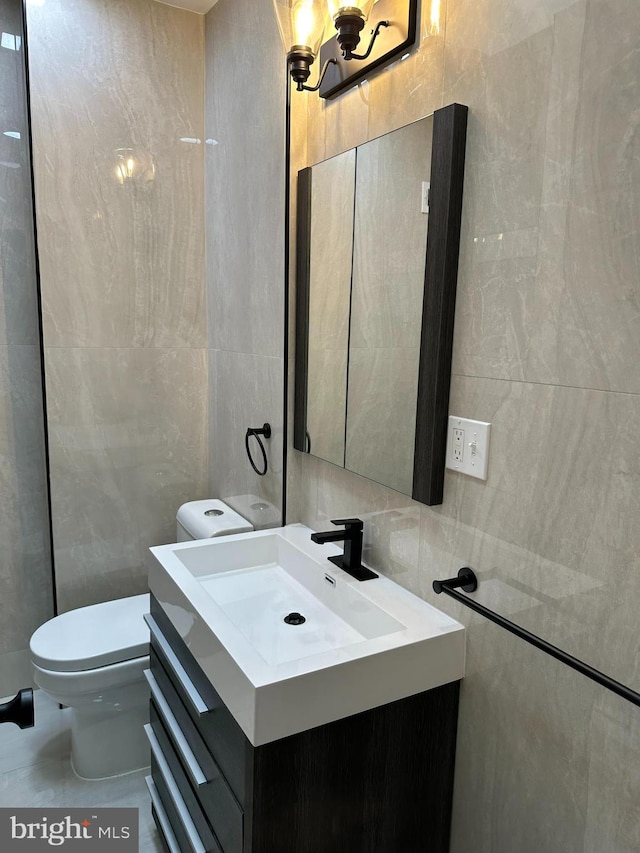 bathroom with tile walls, vanity, and toilet