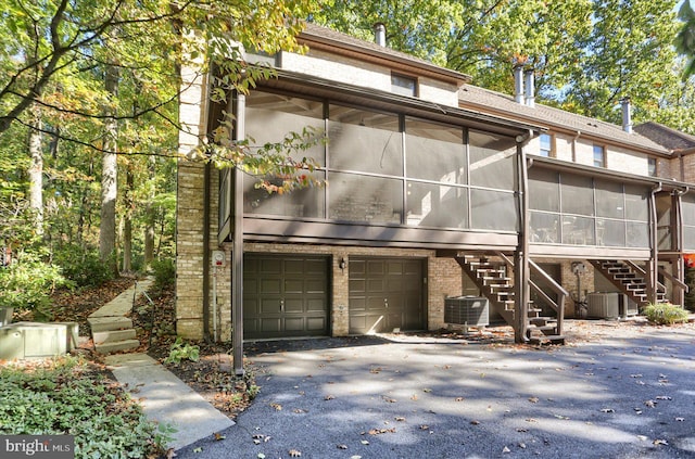 view of front of property featuring central AC, a garage, and a sunroom