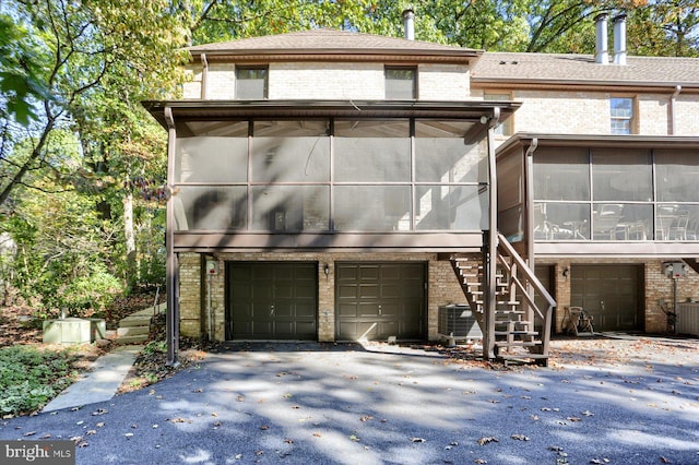 view of front of property featuring a garage, central AC unit, and a sunroom