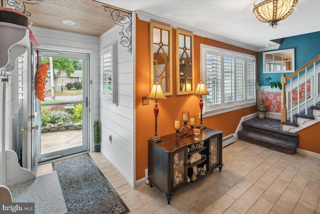 entrance foyer featuring crown molding, wood walls, a wealth of natural light, and a baseboard heating unit