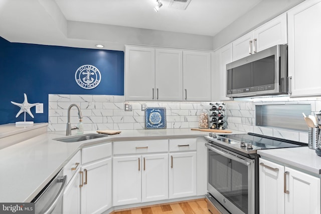 kitchen featuring white cabinets, appliances with stainless steel finishes, light hardwood / wood-style floors, and sink