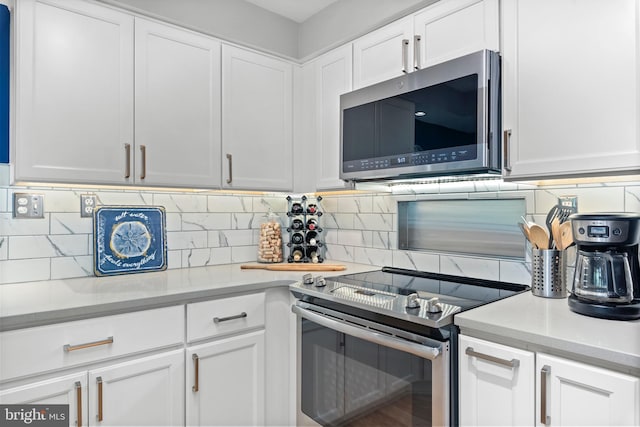 kitchen featuring stainless steel appliances, backsplash, and white cabinetry