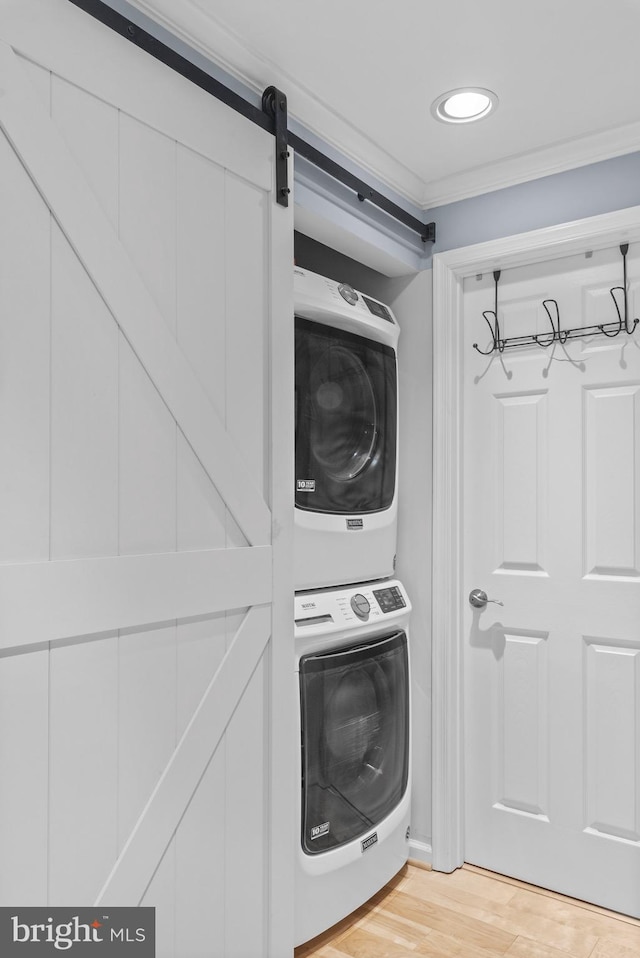 washroom featuring ornamental molding, stacked washing maching and dryer, and light wood-type flooring