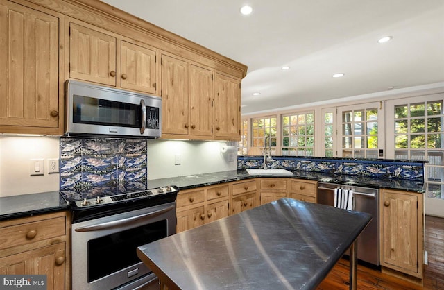 kitchen with dark wood-type flooring, dark stone counters, sink, decorative backsplash, and stainless steel appliances