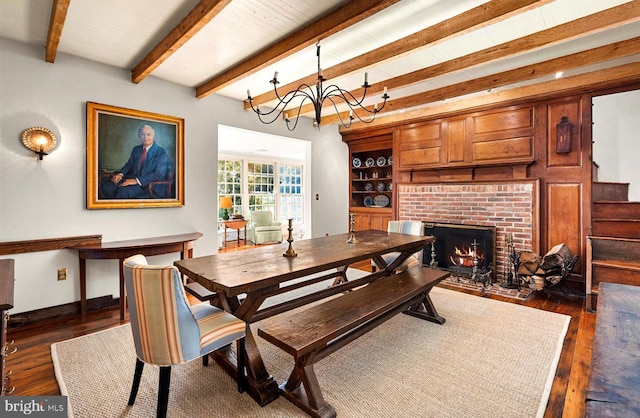 dining area with beamed ceiling, dark hardwood / wood-style floors, a fireplace, and an inviting chandelier