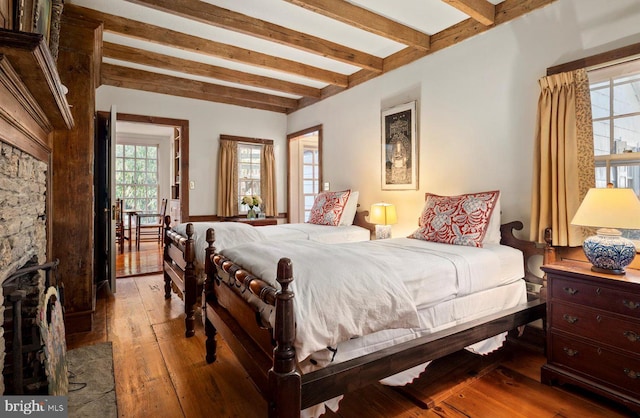 bedroom with wood-type flooring and beam ceiling