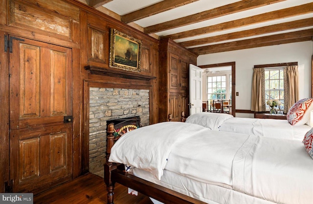 bedroom featuring beam ceiling, dark hardwood / wood-style flooring, and a fireplace