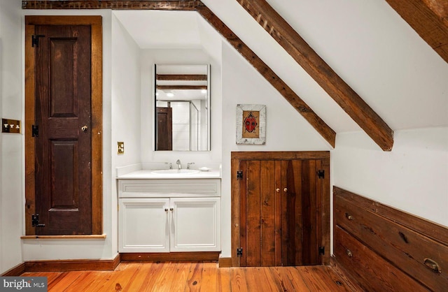 bathroom with hardwood / wood-style floors, lofted ceiling with beams, and vanity