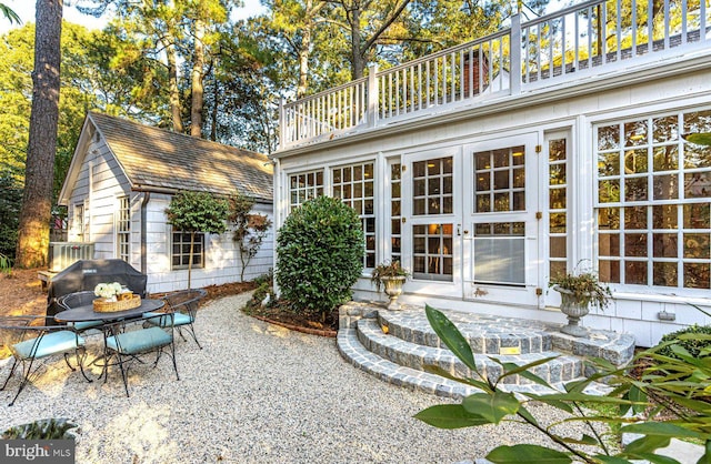 back of property with a balcony, a patio, and french doors