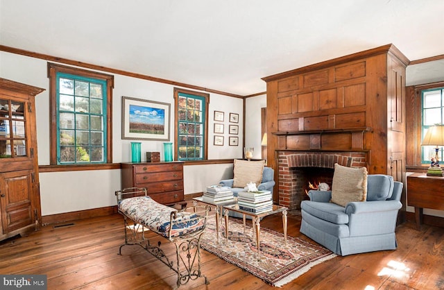 living room with hardwood / wood-style floors, a brick fireplace, and crown molding