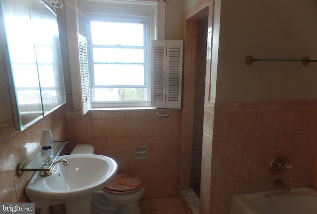 bathroom with tile walls, toilet, and a wealth of natural light