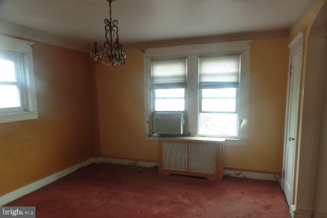 carpeted empty room featuring cooling unit, radiator, and a notable chandelier