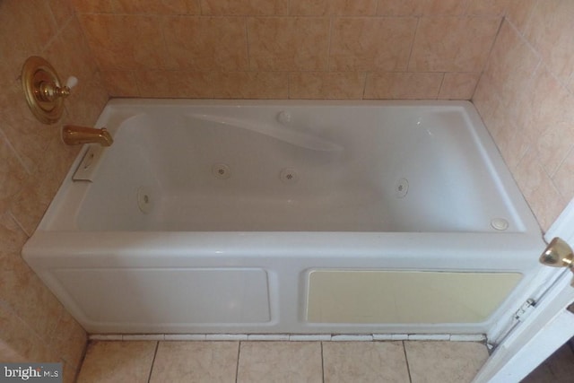 bathroom with a relaxing tiled tub and tile patterned flooring