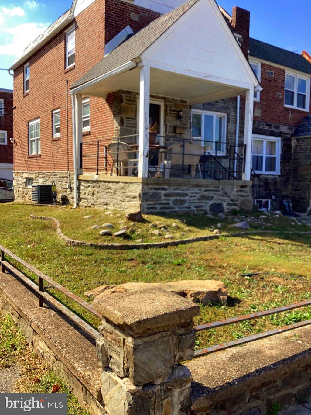 back of house featuring central AC unit, covered porch, and a yard