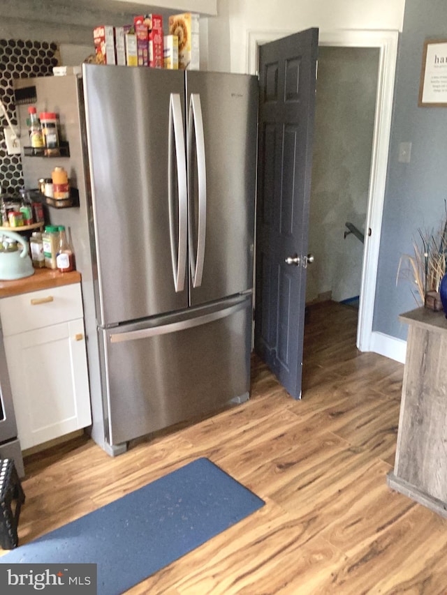 kitchen featuring white cabinets, light wood-type flooring, and stainless steel refrigerator