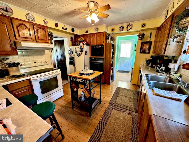 kitchen featuring tasteful backsplash, white appliances, ceiling fan, light hardwood / wood-style flooring, and sink