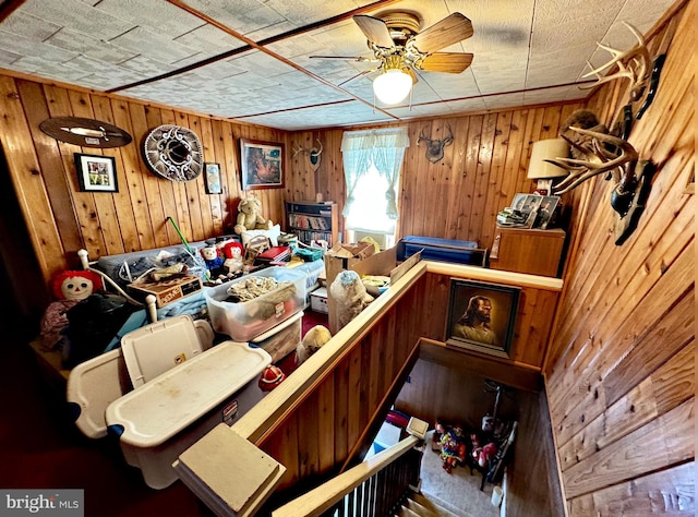 interior space with wood walls and ceiling fan